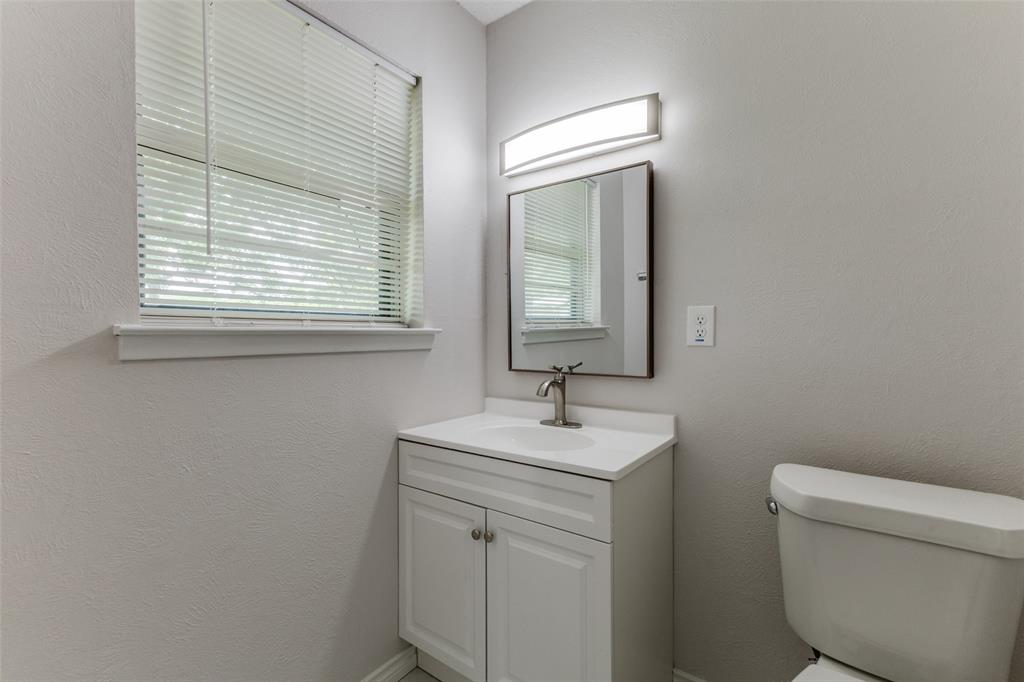 3921 Ambassador Way Balch Springs, TX 75180 - Photo 14 of 25 a bathroom with a toilet sink vanity and mirror