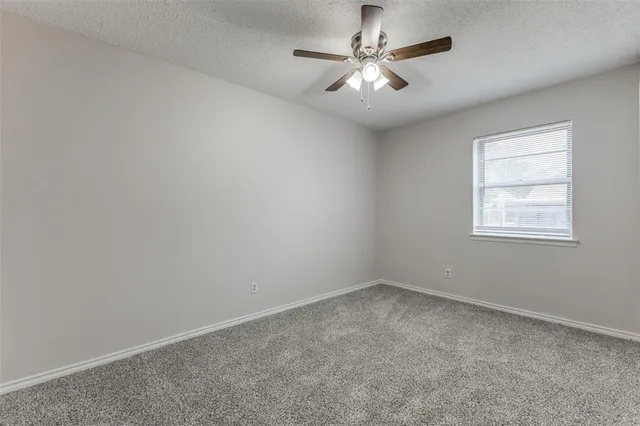 an empty room with a chandelier fan and windows