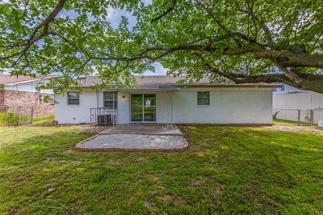 a backyard of a house with plants and large tree