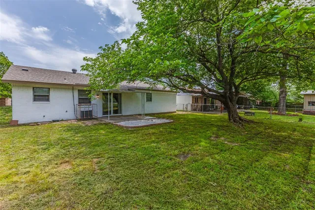 a backyard of a house with plants and large tree