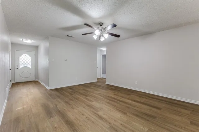 a view of an empty room with window and wooden floor