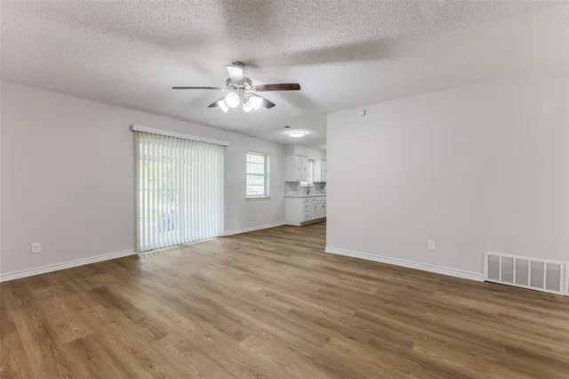 a view of an empty room with a window and wooden floor