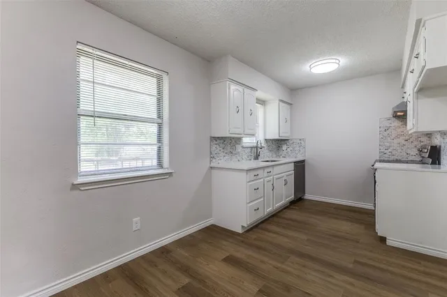 a kitchen with a white wooden cabinets sink and window