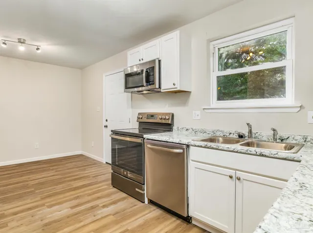 a kitchen with stainless steel appliances granite countertop a stove a sink and a microwave
