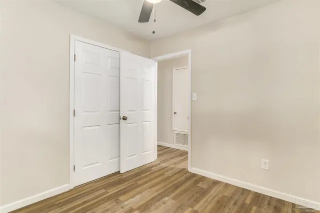 an empty room with wooden floor cabinet and windows