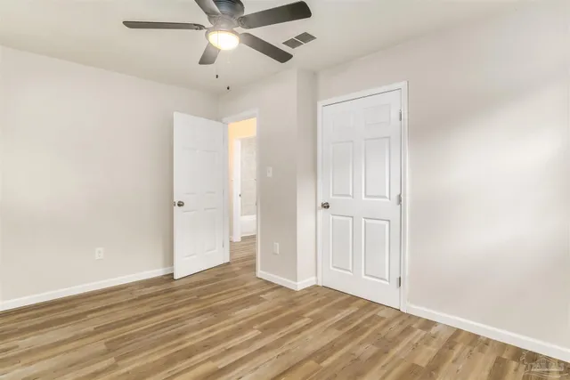 a view of empty room with wooden floor and fan