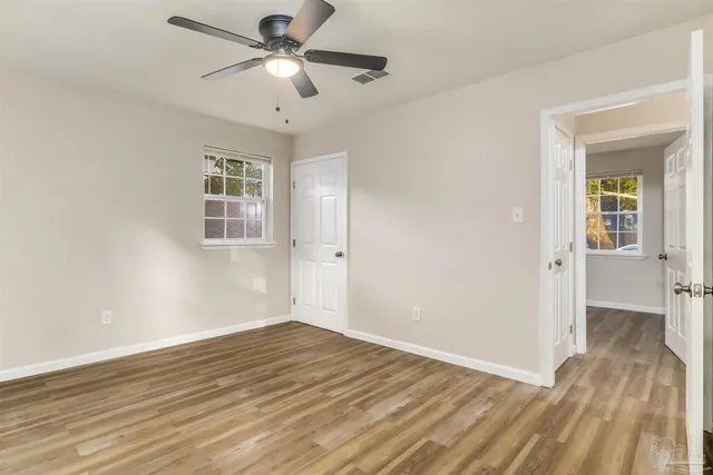 a view of empty room with wooden floor and fan