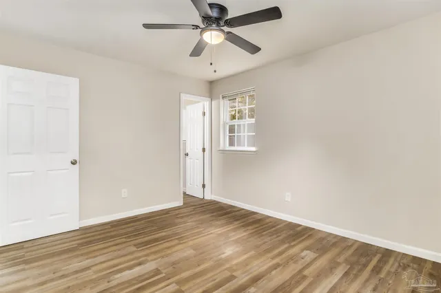 a view of empty room with wooden floor and fan