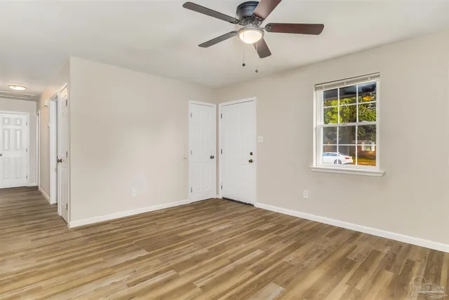 a view of empty room with wooden floor and fan