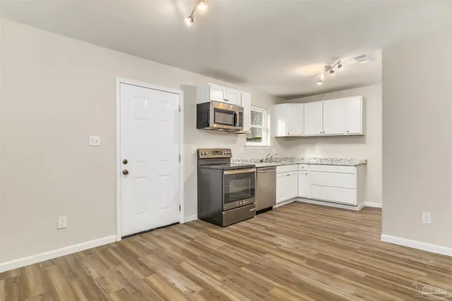 a kitchen with granite countertop a sink cabinets and stainless steel appliances