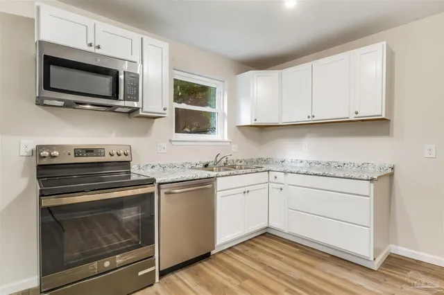 a kitchen with cabinets stainless steel appliances and a wooden floor