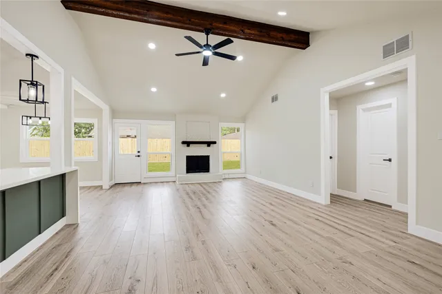 a view of an empty room with window and wooden floor