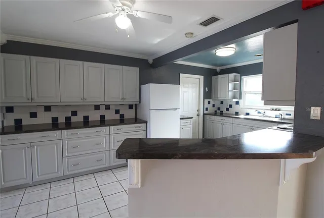 a kitchen with stainless steel appliances granite countertop a refrigerator a sink dishwasher a stove with white cabinets and countertops