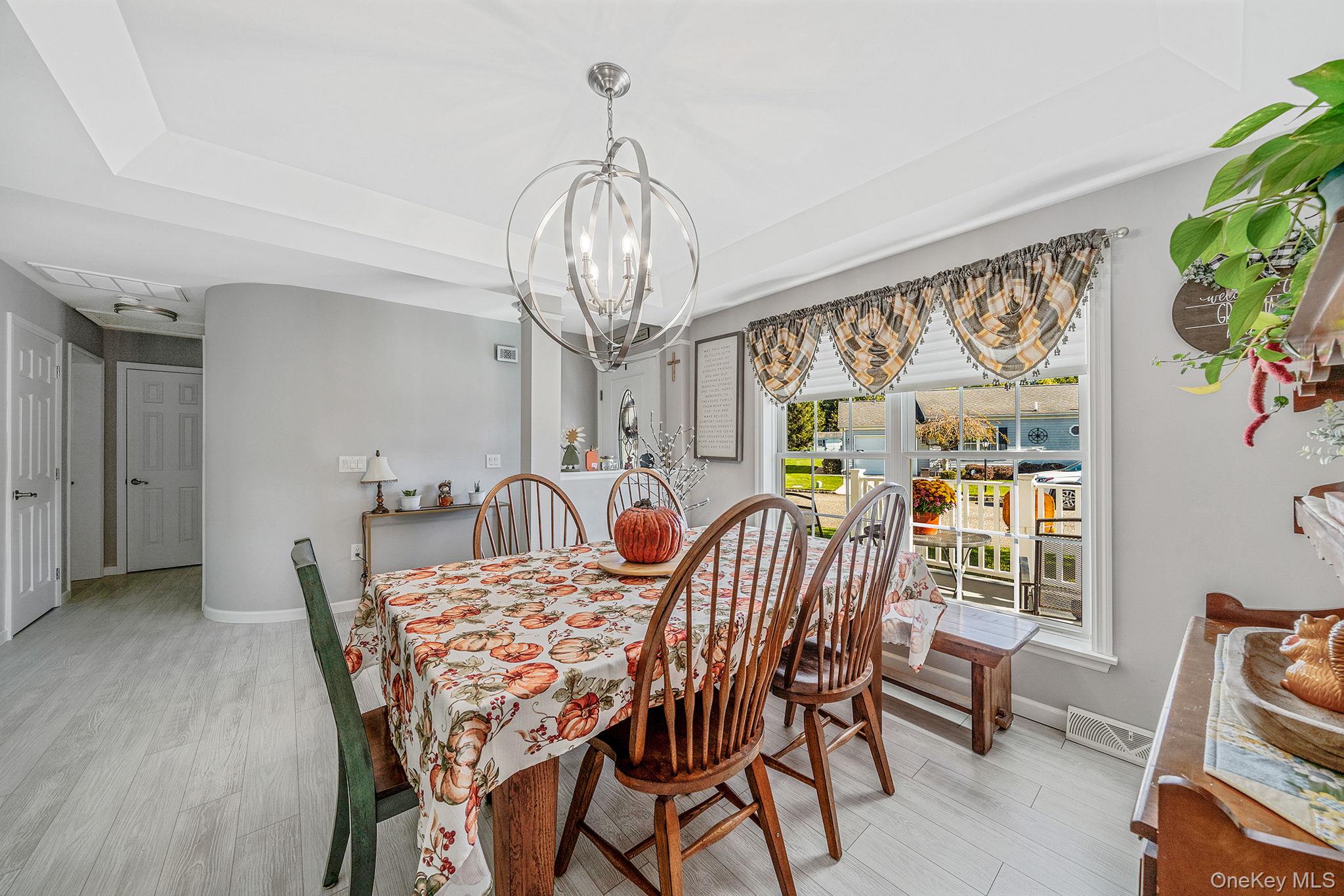 1407 Middle Road, Unit 258 Calverton, NY 11933 - Photo 13 of 50 a view of a dining room with furniture a chandelier and wooden floor