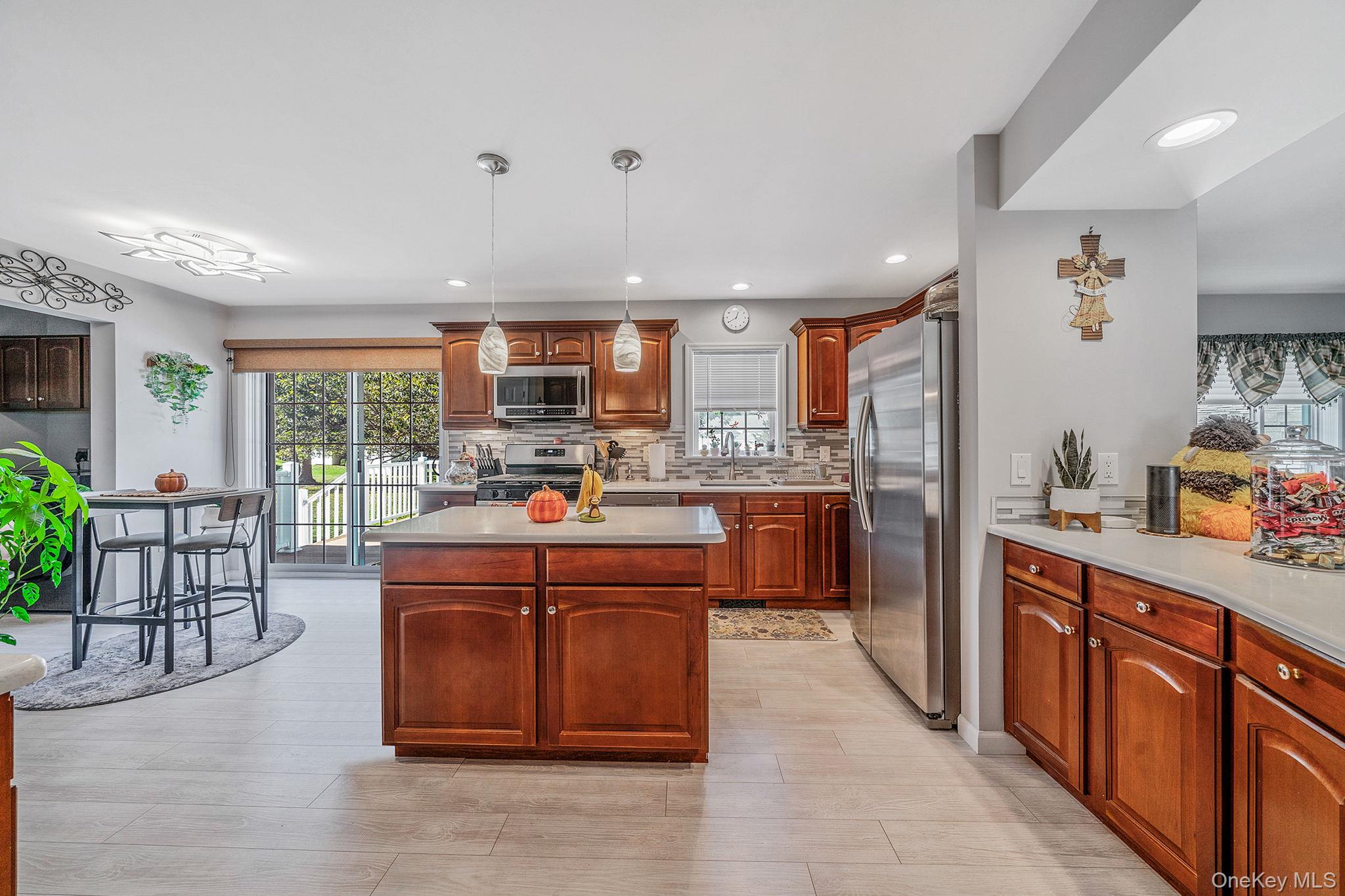 1407 Middle Road, Unit 258 Calverton, NY 11933 - Photo 19 of 50 a kitchen with stainless steel appliances granite countertop a refrigerator a sink dishwasher a stove and a dining table with wooden floor