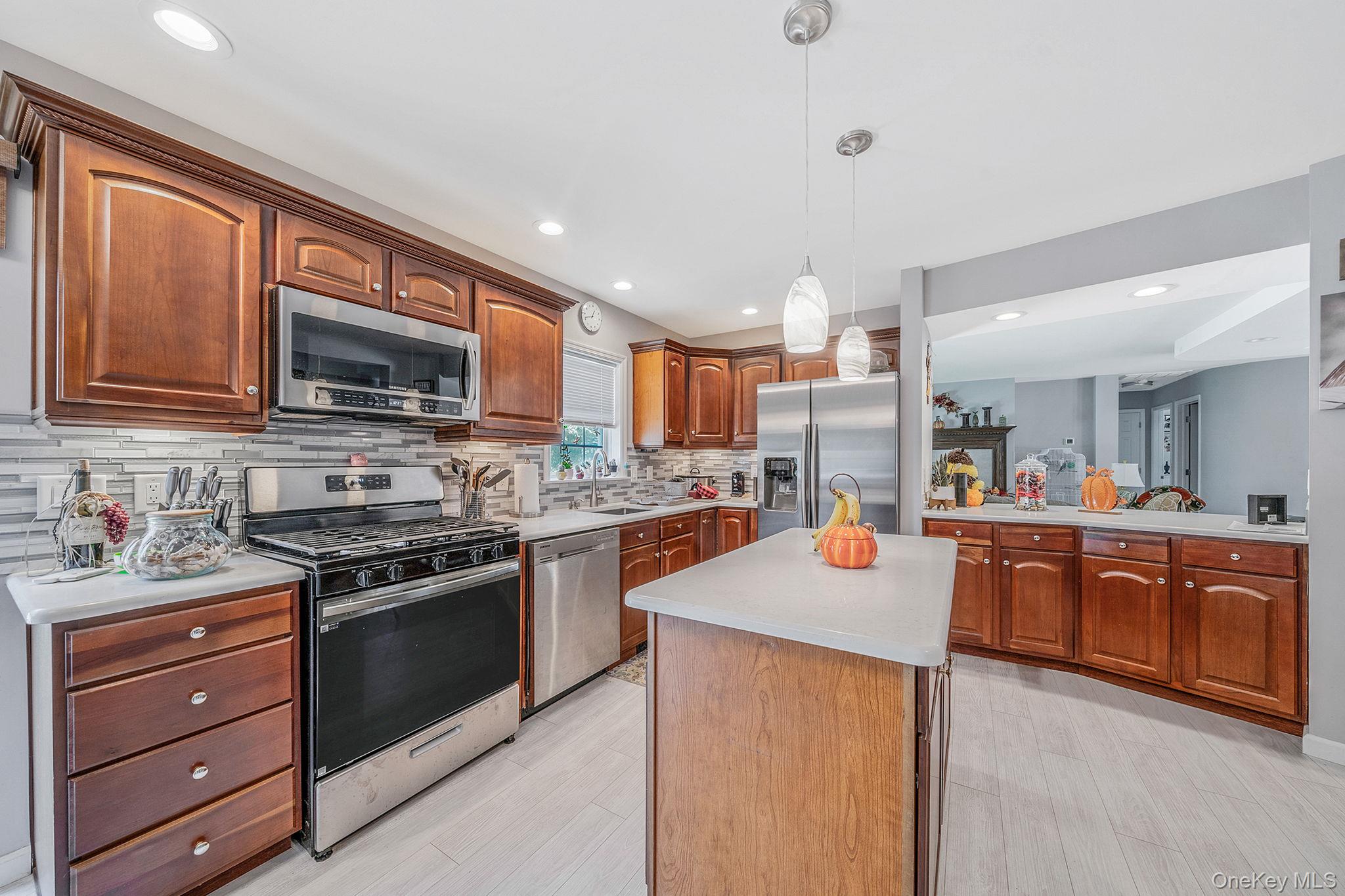 1407 Middle Road, Unit 258 Calverton, NY 11933 - Photo 22 of 50 a kitchen with stainless steel appliances granite countertop a sink stove microwave and refrigerator