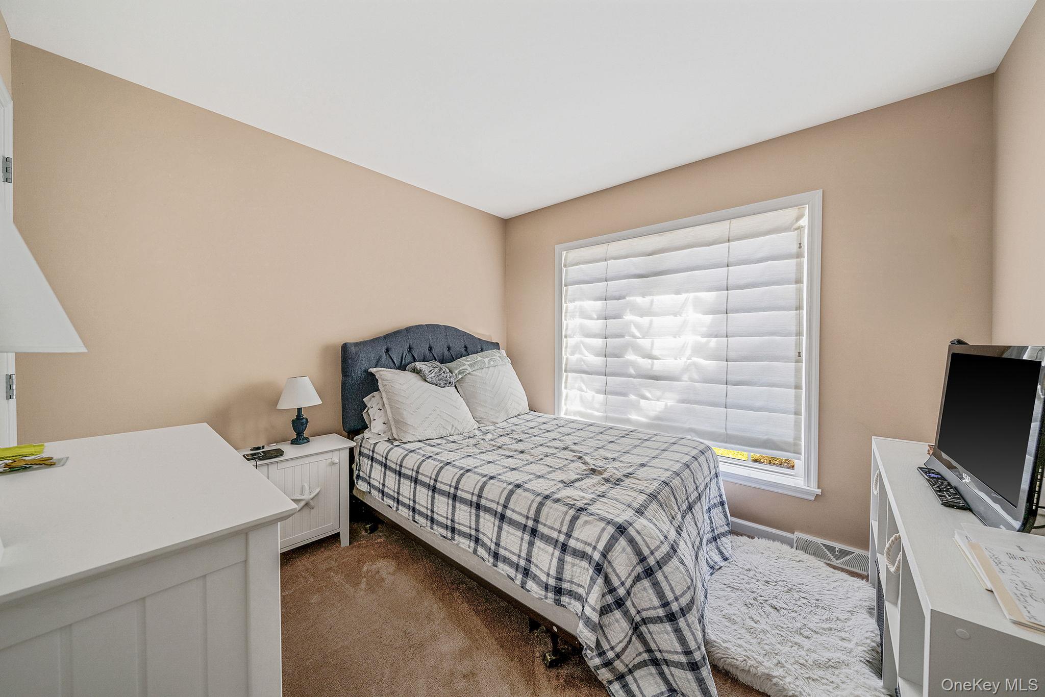 1407 Middle Road, Unit 258 Calverton, NY 11933 - Photo 32 of 50 a bedroom with a bed and a flat screen tv