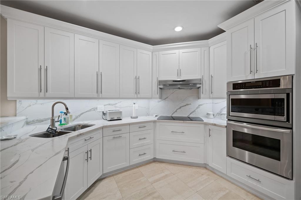 261 Colonade Circle, Unit 2701 Naples, FL 34103 - Photo 13 of 49 a kitchen with granite countertop white cabinets stainless steel appliances and sink