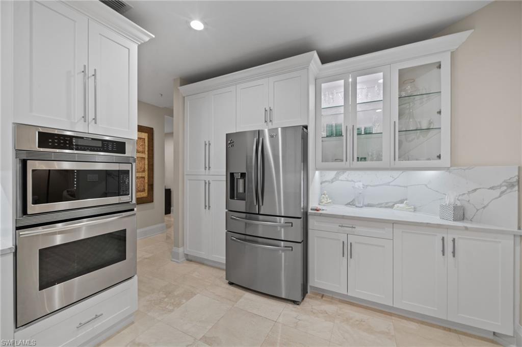 261 Colonade Circle, Unit 2701 Naples, FL 34103 - Photo 15 of 49 a kitchen with white cabinets and stainless steel appliances