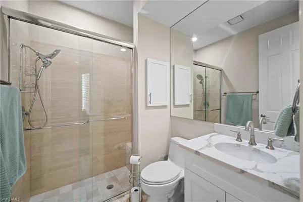 a bathroom with a granite countertop shower sink vanity and toilet