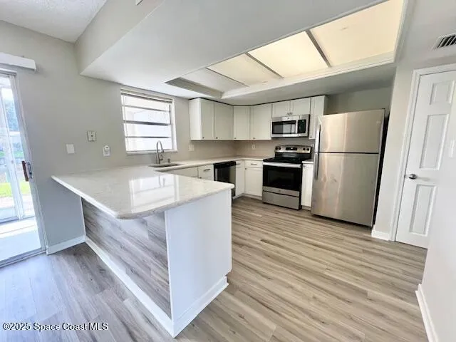 a kitchen with a refrigerator a sink and dishwasher with wooden floor