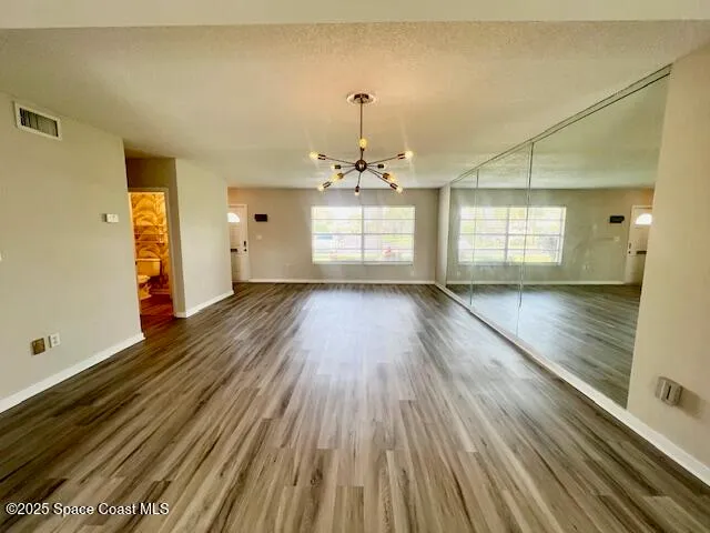 an empty room with wooden floor a ceiling fan and windows