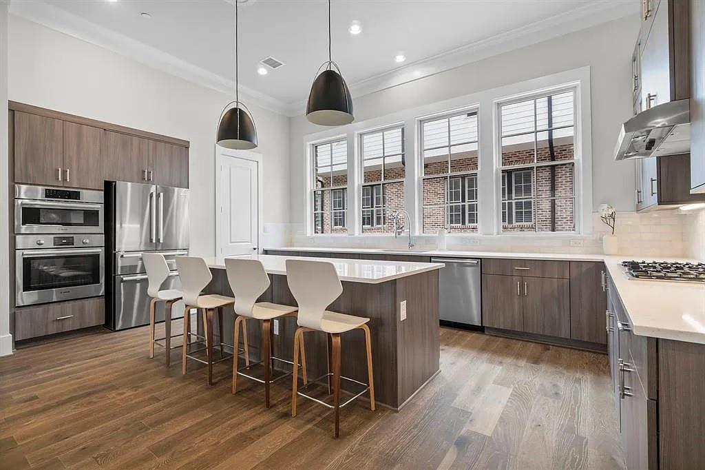 a kitchen with stainless steel appliances granite countertop a stove a refrigerator a sink a dining table and chairs with wooden floor