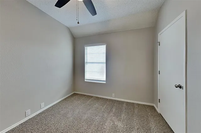 an empty room with a window and a fan