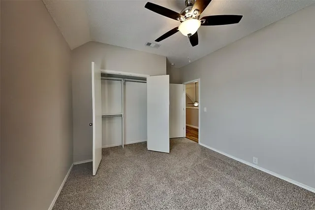 an empty room with closet and a ceiling fan