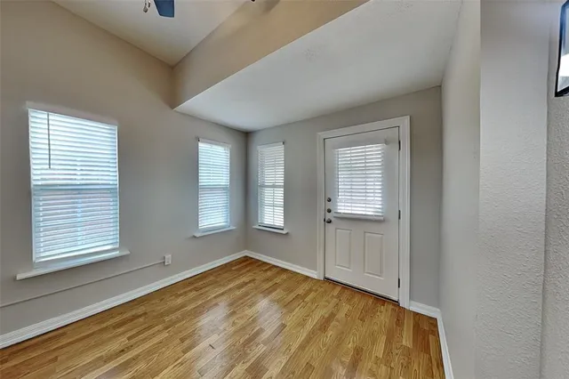 a view of empty room with wooden floor and fan