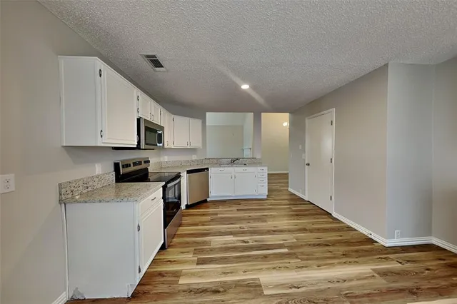 a kitchen with stainless steel appliances granite countertop a stove a sink and white cabinets