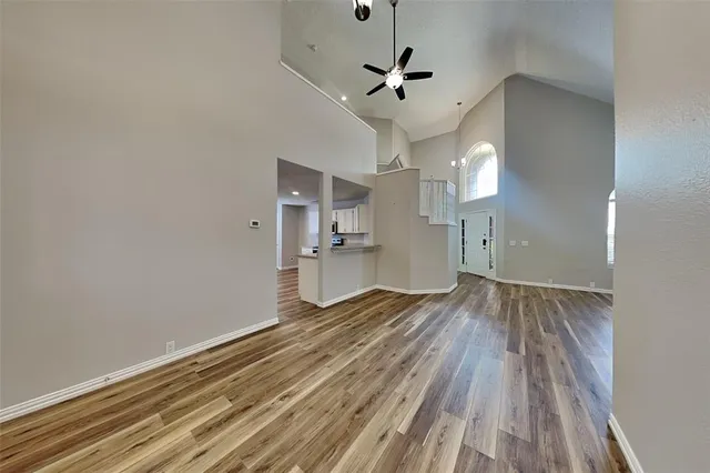 a view of empty room with wooden floor and ceiling fan