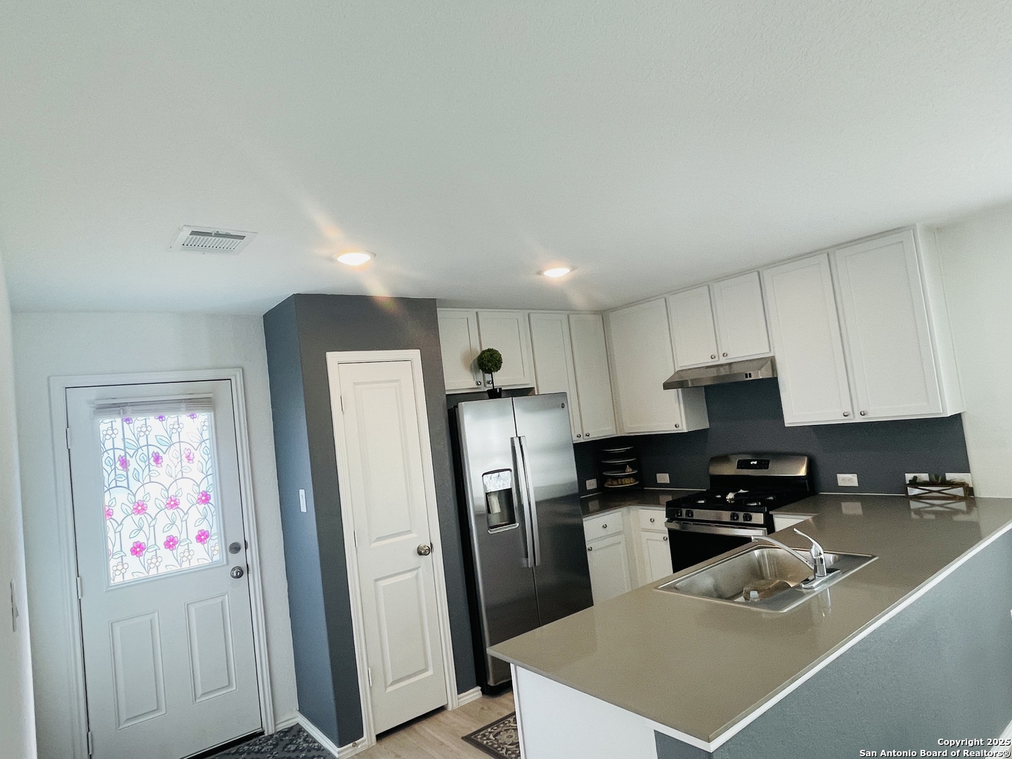 6948 Calcite Trail Elmendorf, TX 78112 - Photo 7 of 12 a kitchen with stainless steel appliances a refrigerator a sink a stove a microwave a counter top and cabinets