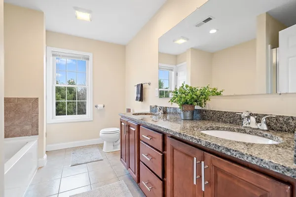 a bathroom with a granite countertop tub a sink and a mirror