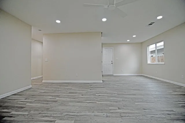 a view of an empty room with wooden floor and a window