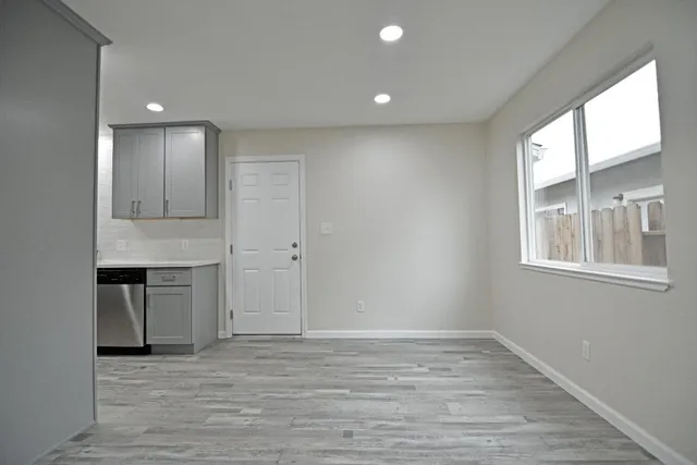 a view of an empty room with a window and wooden floor