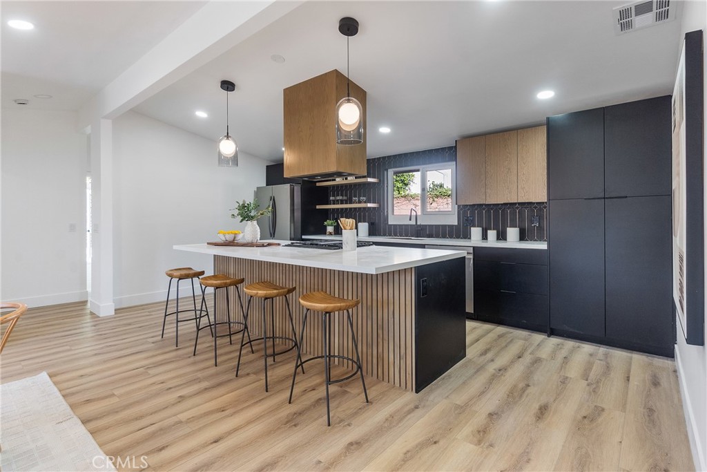 6909 De Celis Place Van Nuys, CA 91406 - Photo 3 of 46 a kitchen with stainless steel appliances kitchen island granite countertop a sink a stove a dining table and chairs