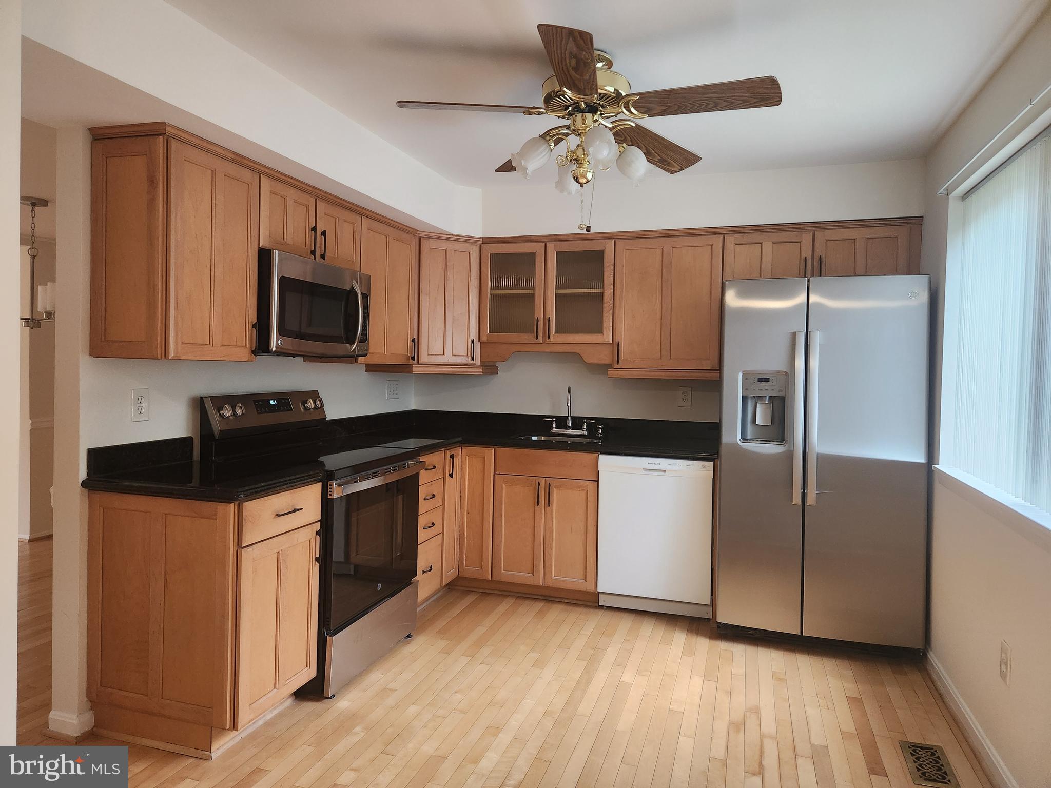 7104 Lasting Light Way Columbia, MD 21045 - Photo 3 of 40 a kitchen with granite countertop a refrigerator a stove a sink a microwave a dining table and chairs with wooden floor