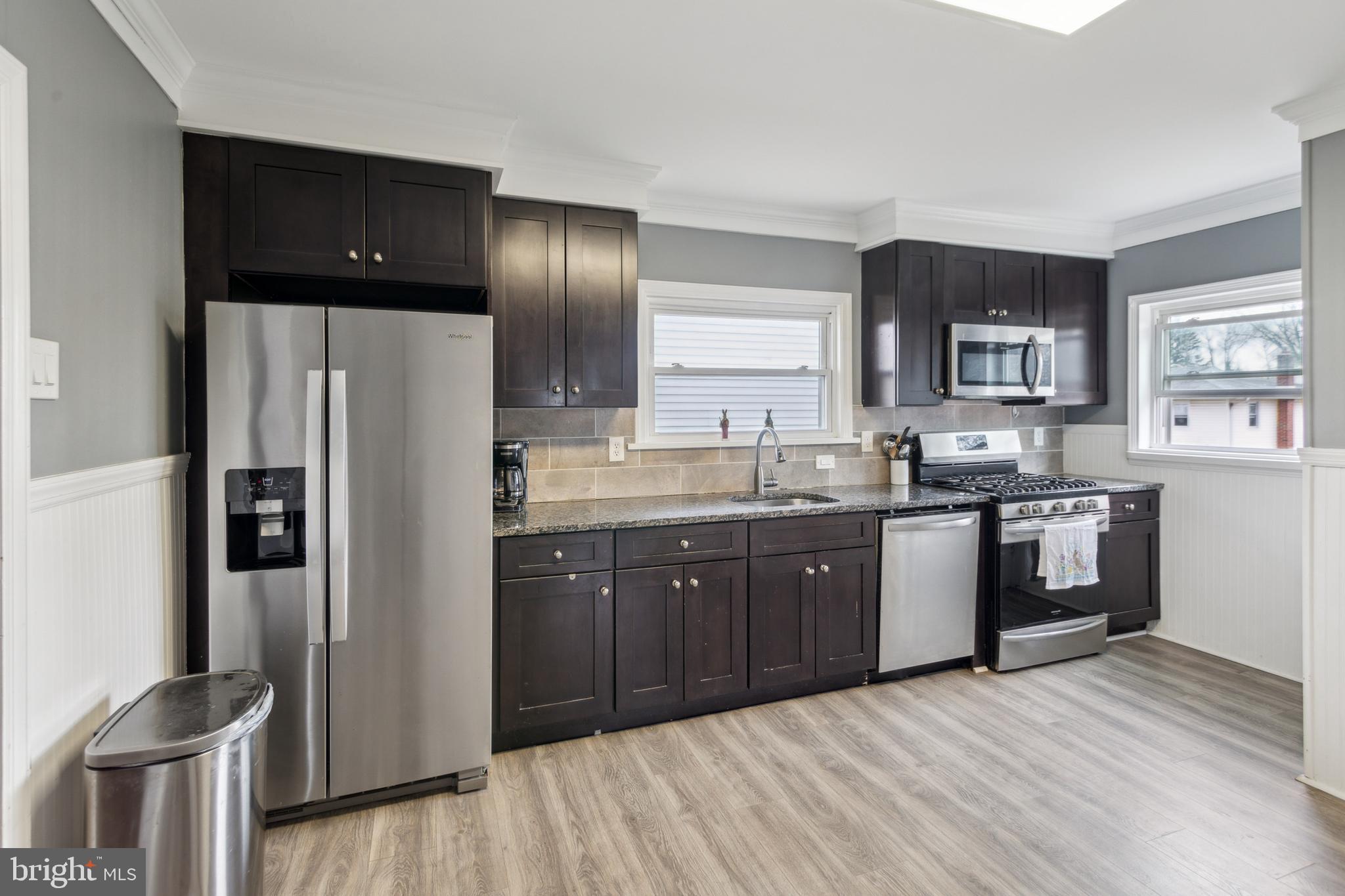812 Lambert Avenue Mount Ephraim, NJ 08059 - Photo 7 of 24 a kitchen with stainless steel appliances granite countertop a refrigerator a sink dishwasher and wooden cabinets with wooden floor
