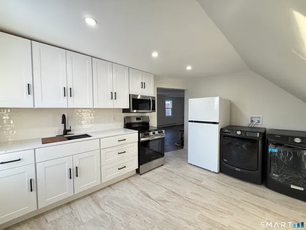 a kitchen with granite countertop white cabinets and stainless steel appliances