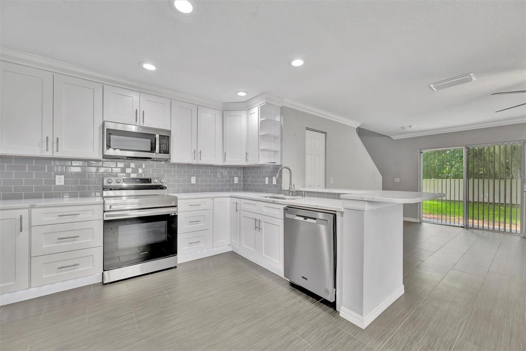 2928 Royal Tuscan Lane Valrico, FL 33594 - Photo 16 of 62 a kitchen with granite countertop white cabinets and white appliances