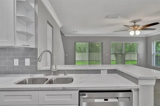 a open kitchen with granite countertop a white cabinets and chandelier