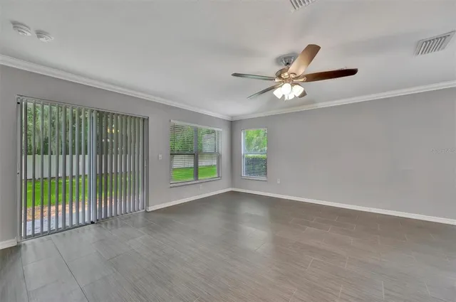 an empty room with windows and fan