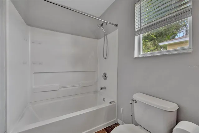 an empty room with windows and ceiling fan