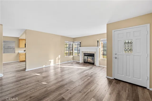 an empty room with wooden floor fireplace and windows