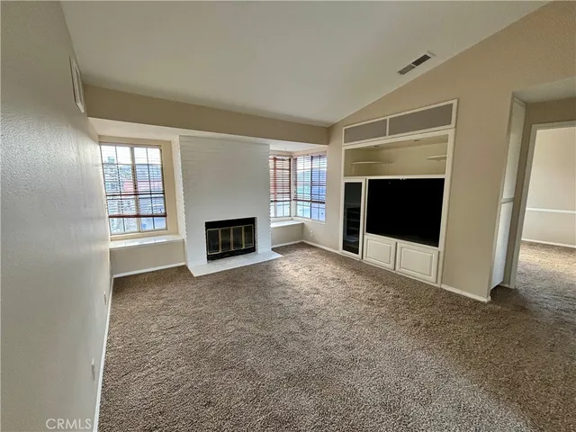 en empty room with windows and fireplace