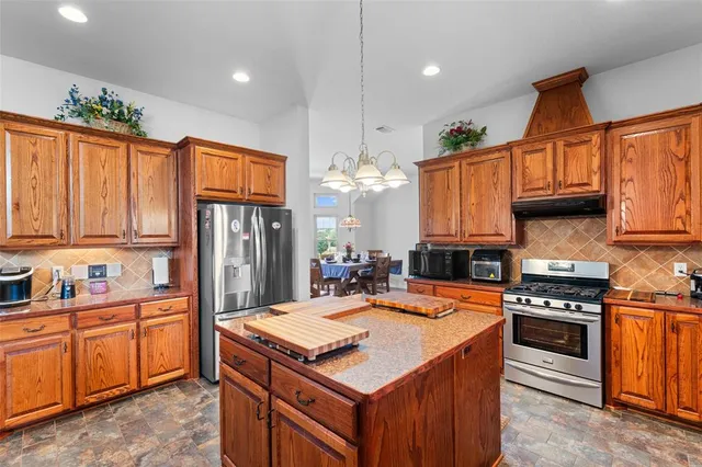 a kitchen with stainless steel appliances granite countertop a refrigerator and a stove top oven