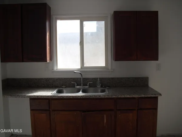 a kitchen with granite countertop white cabinets sink and window