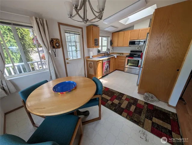 a kitchen with stainless steel appliances a stove a refrigerator a sink a dining table and chairs