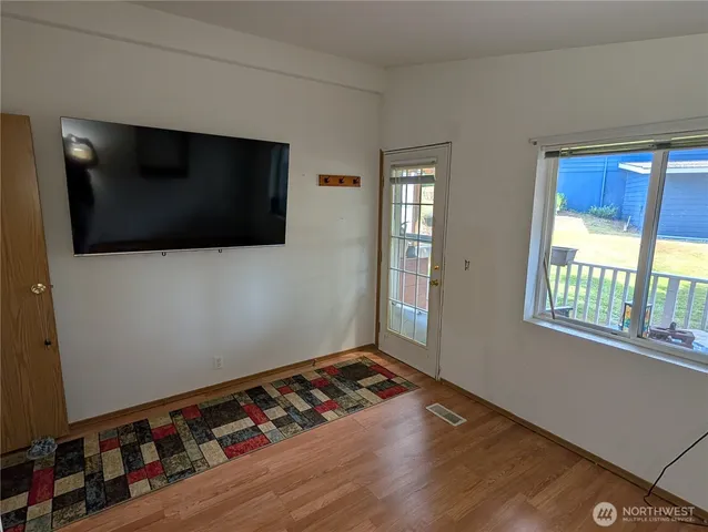 a view of an empty room with wooden floor and a window